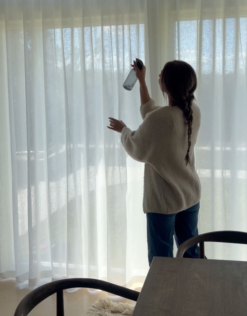 Kvinna sprayar gardiner med linnevatten